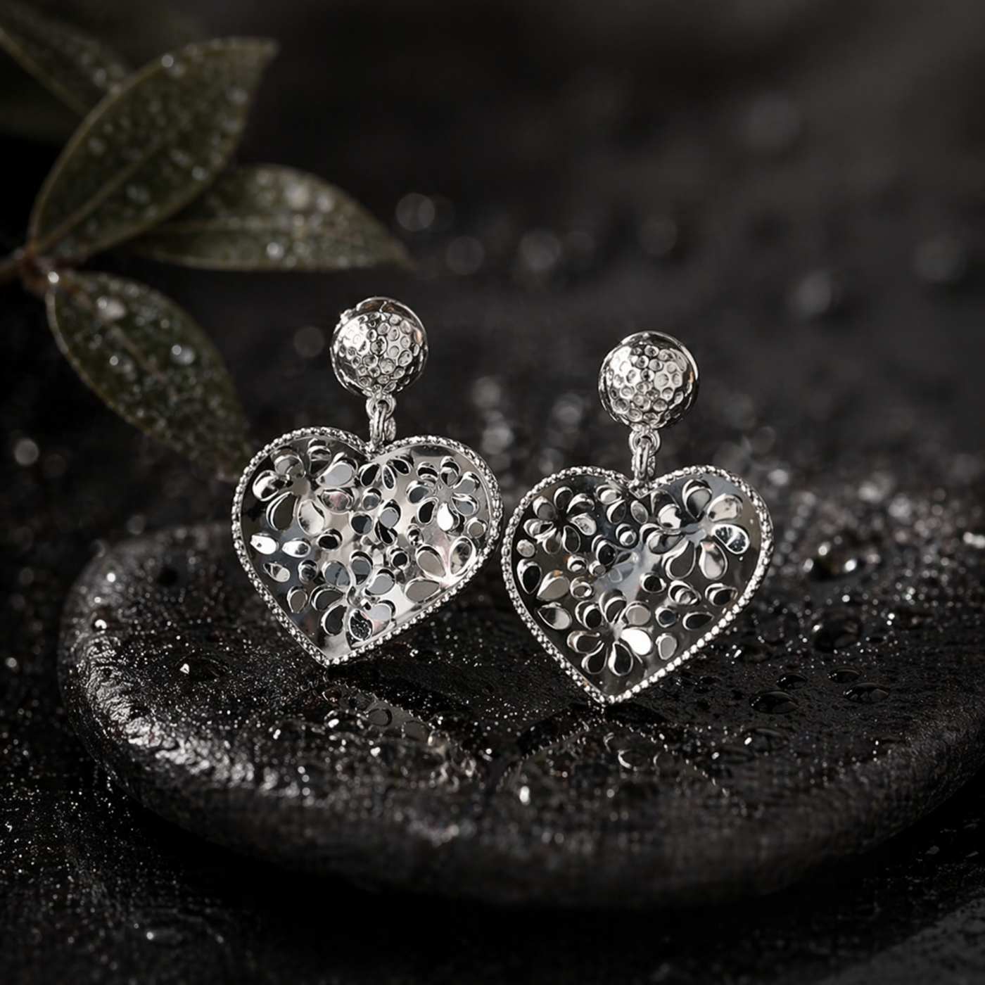 Heart-shaped silver earrings on a dark surface with a blurred background