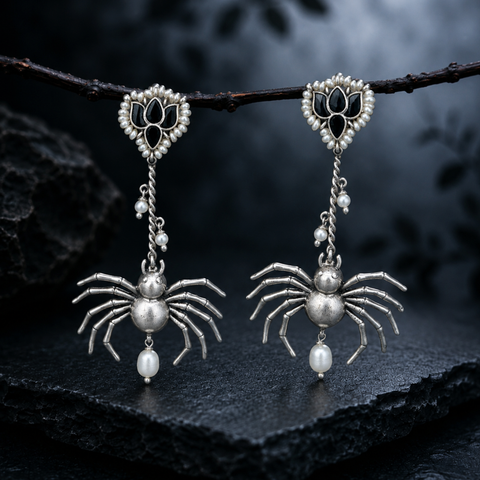 Sterling silver gothic spider drop earrings with black onyx lotus stud, hanging from a branch