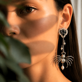 Close-up of a model wearing sterling silver gothic spider drop earrings with pearl accent