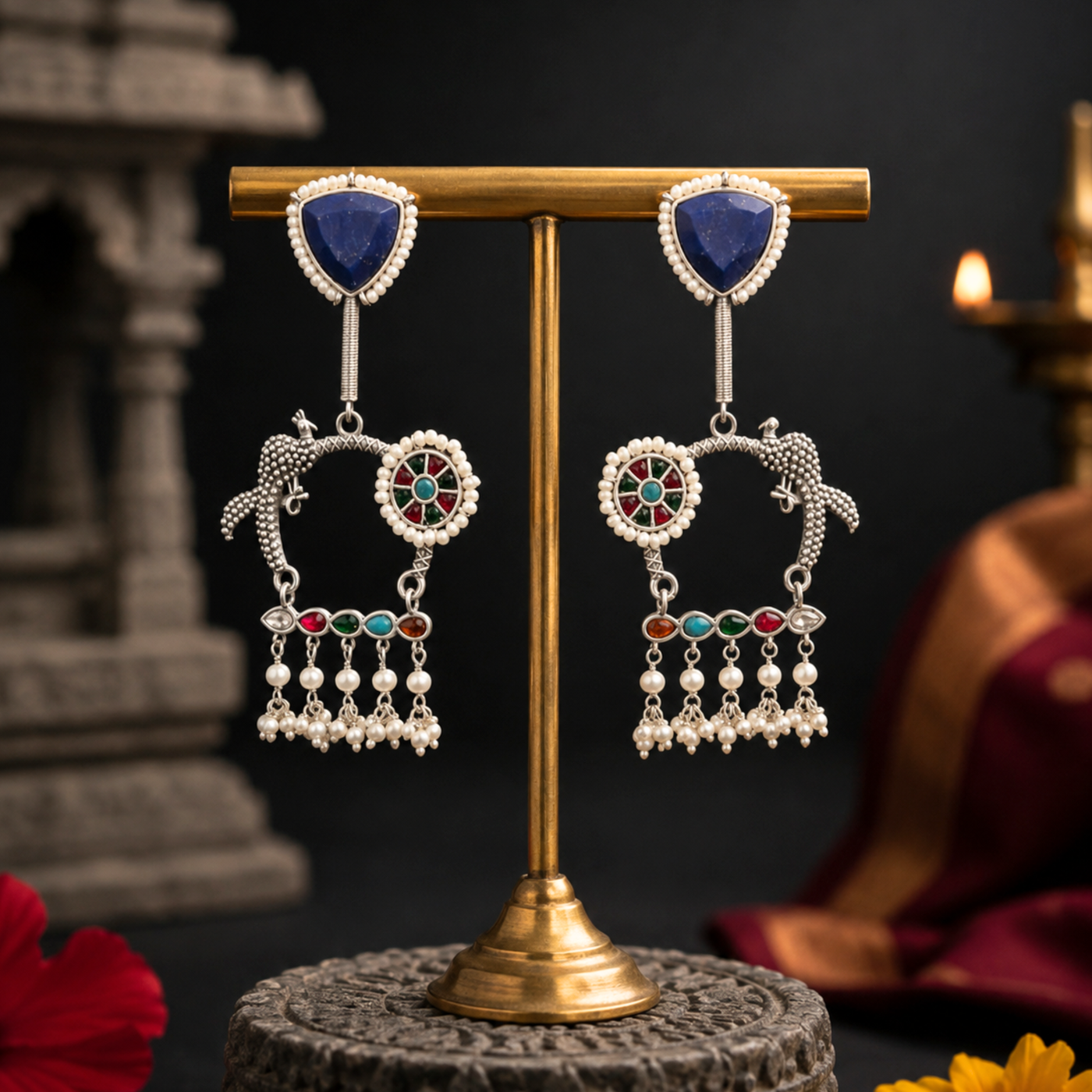 Sterling silver peacock kundan jhumka earrings with lapis lazuli and pearl tassels on a brass stand